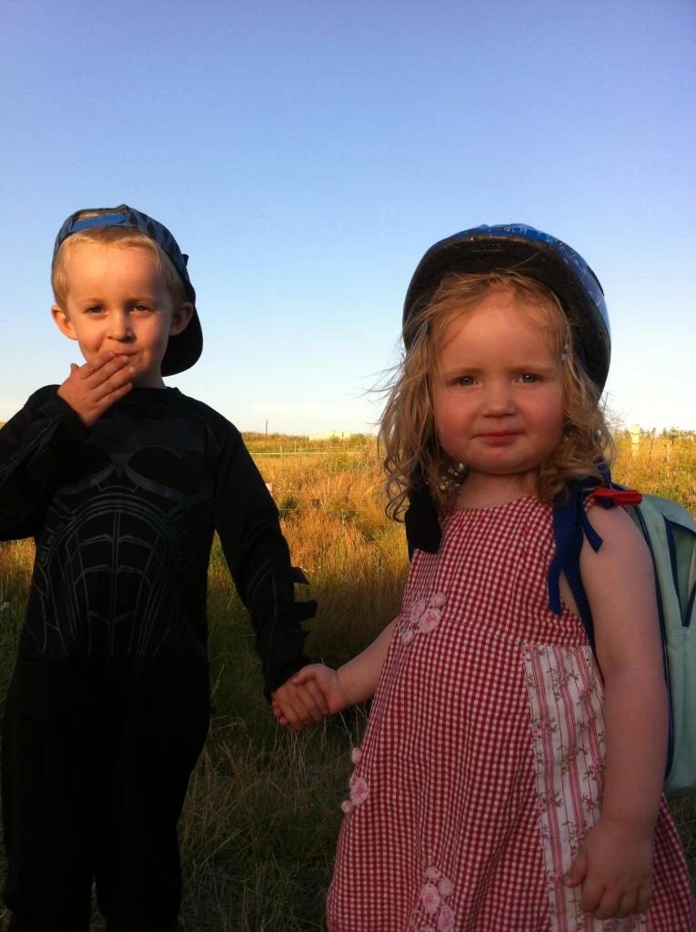 Pige og dreng holder i hånd med blå himmel i baggrunden.