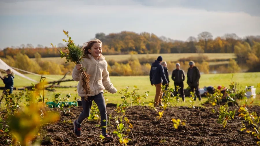 Pige løber med små træer. Foto: Andreas B. Elkjær. INSP Media.