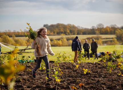 Pige løber med små træer. Foto: Andreas B. Elkjær. INSP Media.